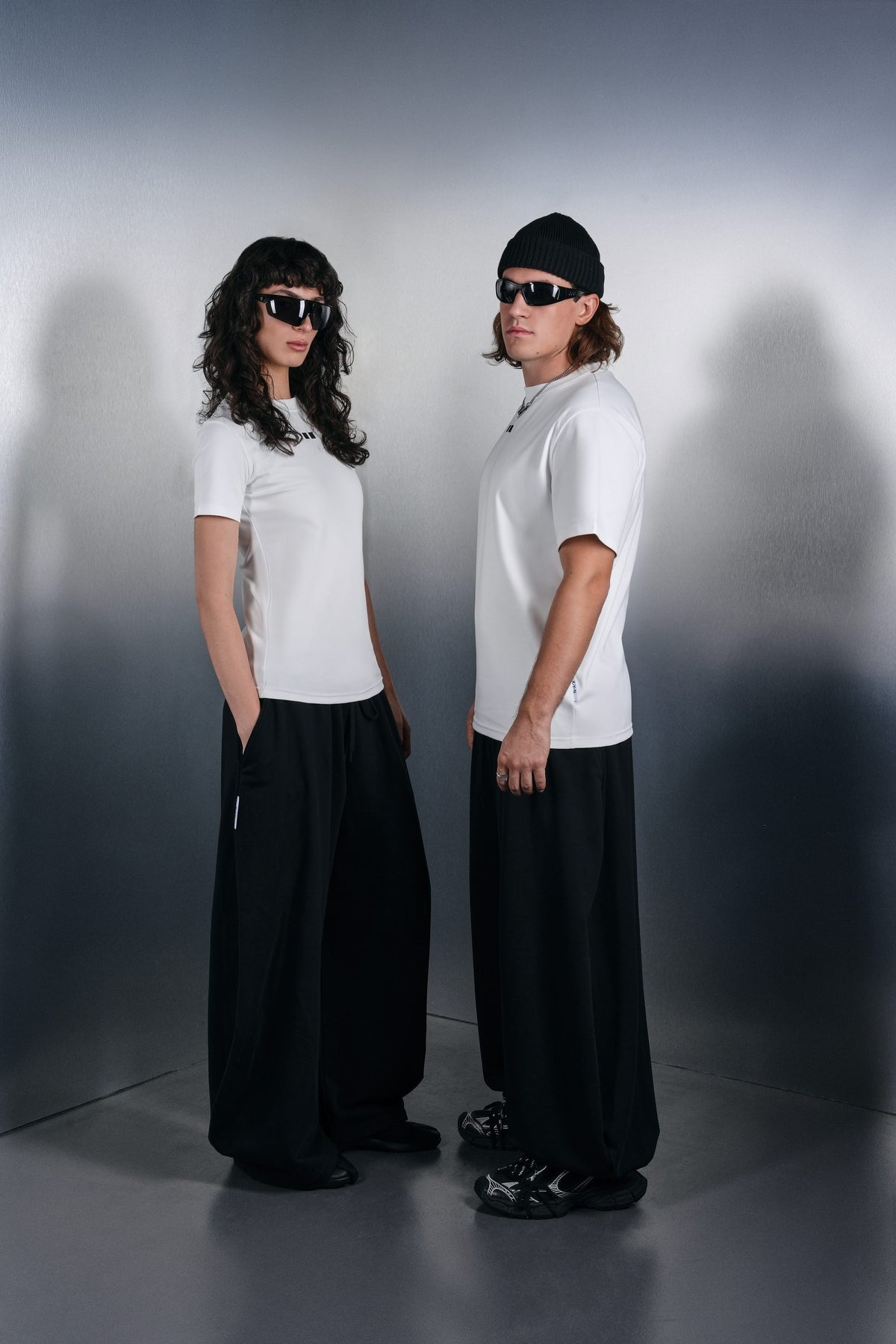 Two people in white KYN T-shirts and wide black trousers