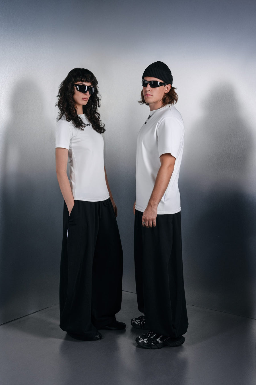 Two people in white KYN T-shirts and wide black trousers