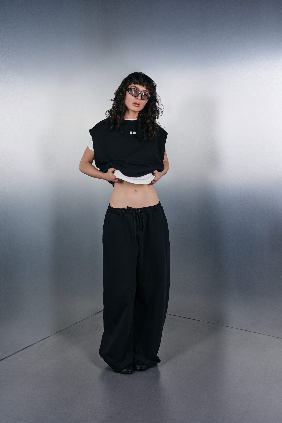 Black Drop-Shoulder vest over a white T-shirt and black trousers