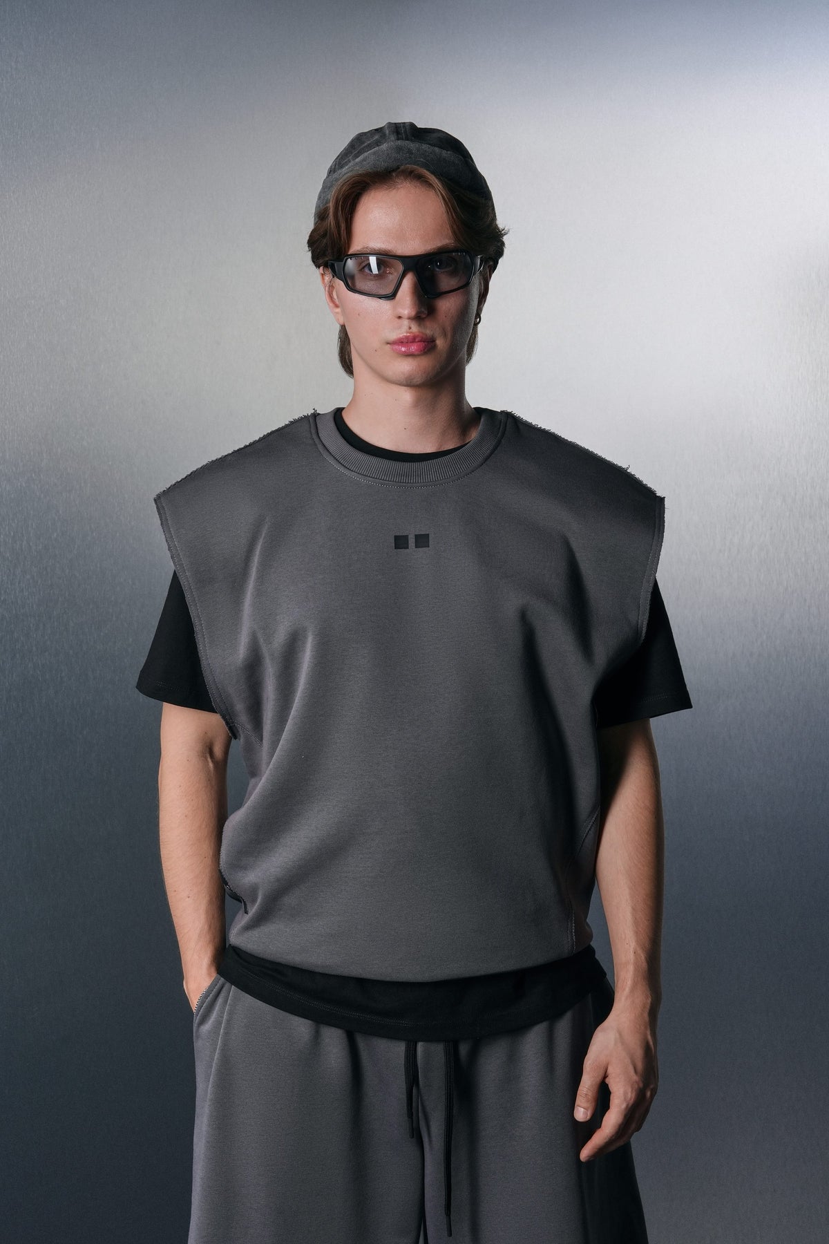 Grey KYN Drop-Shoulder vest over a black tee and grey trousers