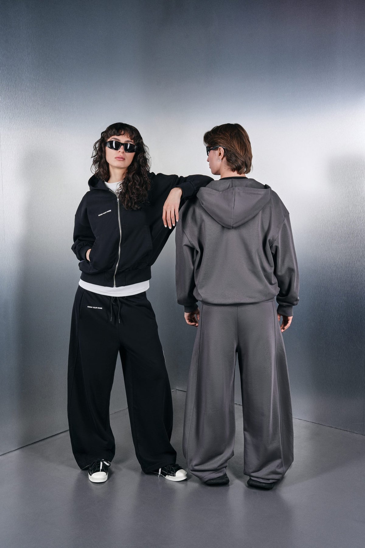 Black and grey KYN hoodies, side and back view